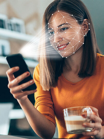 Woman with smartphone in hand uses facial recognition.